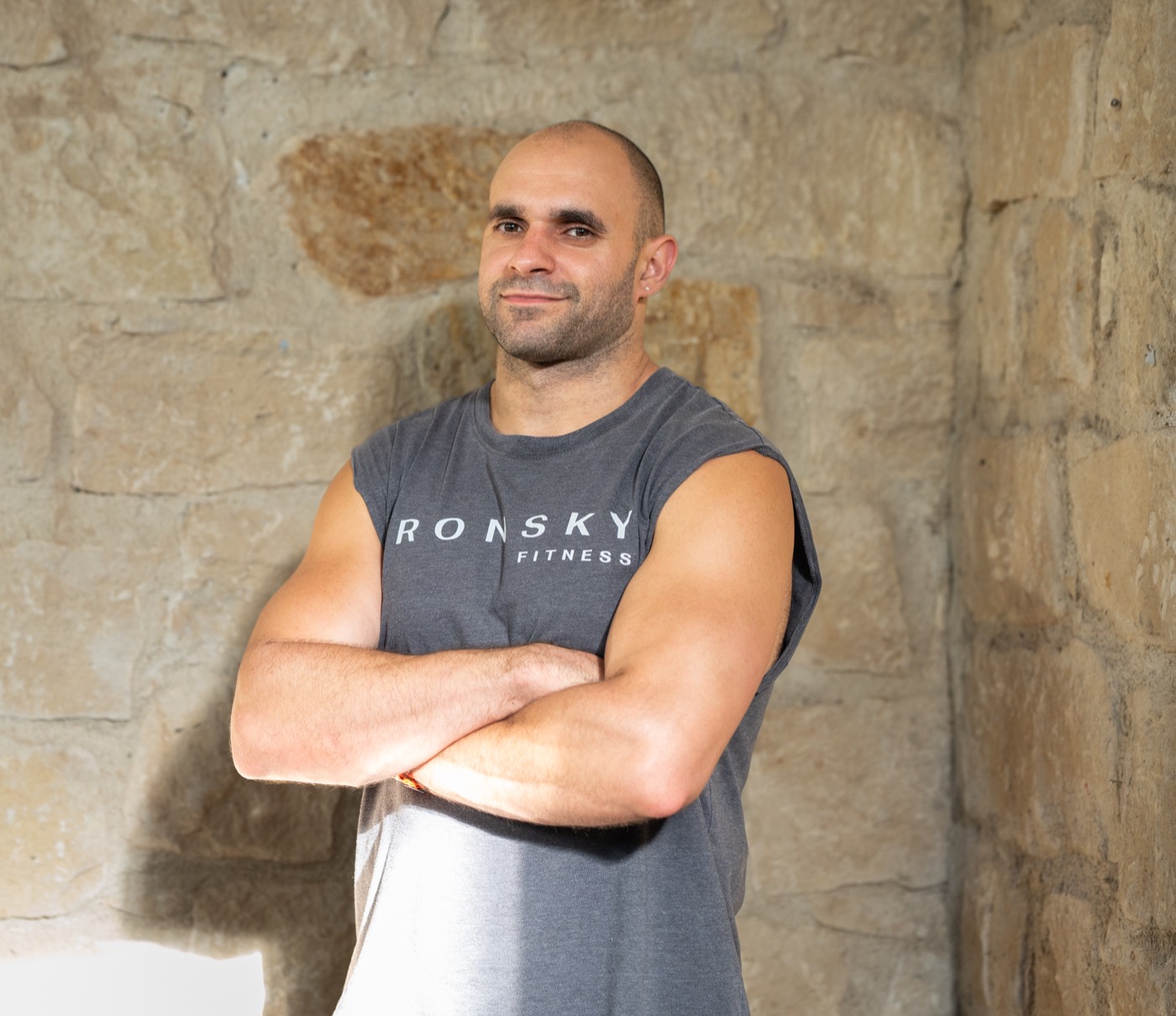 An IRONSKY coach, arms folded, against the stone wall.