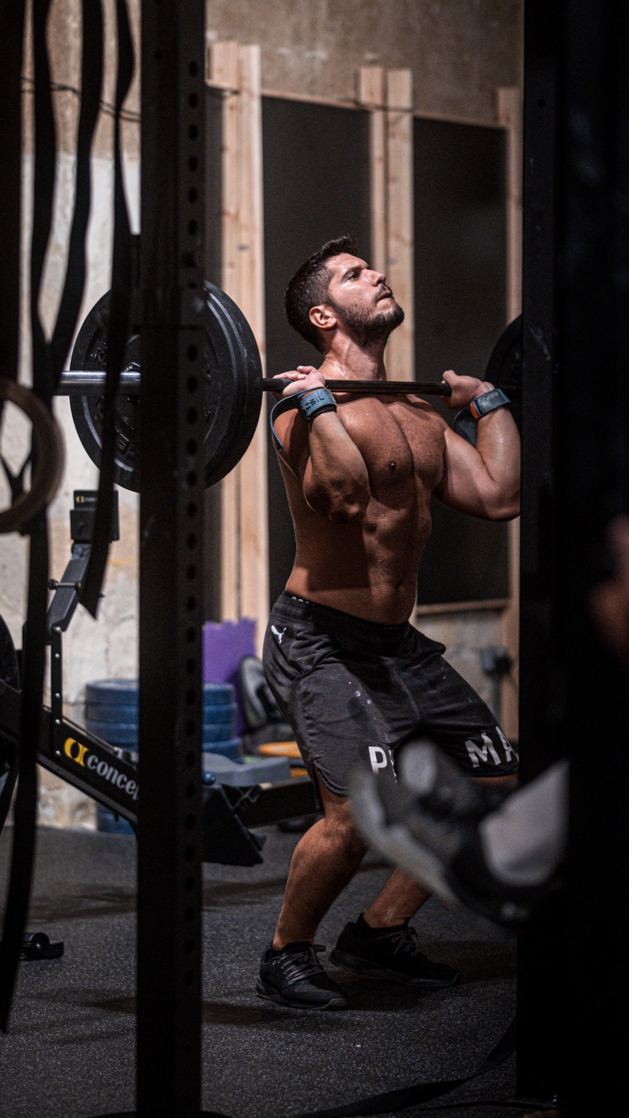 A member holding a loaded barbell in the front rack position.