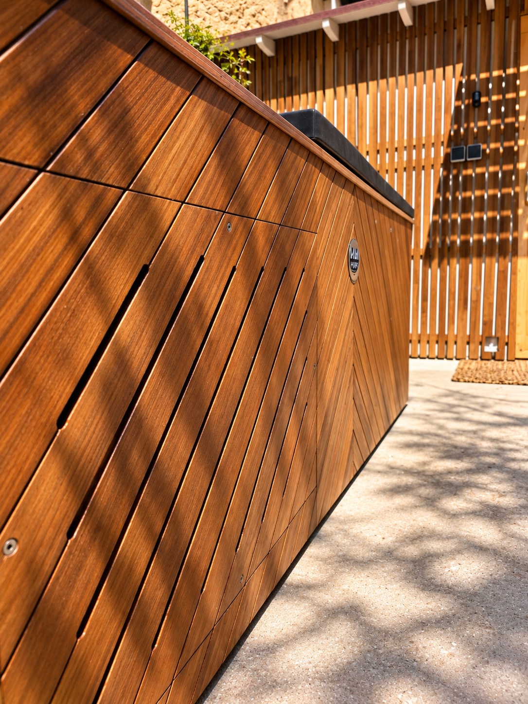 The wooden side of the cold plunge in afternoon light.